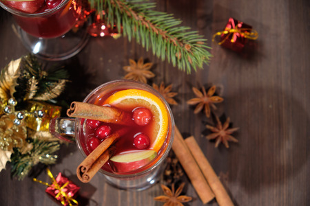Mulled wine on a wooden background with candles, pine branches and Christmas lightsの写真素材