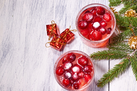 Glasses with cranberry juice on white wooden background with pine branch in the backgroundの写真素材