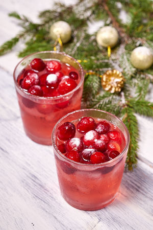 Glasses with cranberry juice on white wooden background with pine branch in the backgroundの写真素材