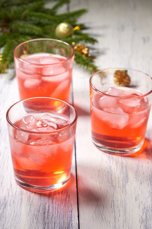 Glasses with cranberry juice on white wooden background with pine branch in the backgroundの写真素材