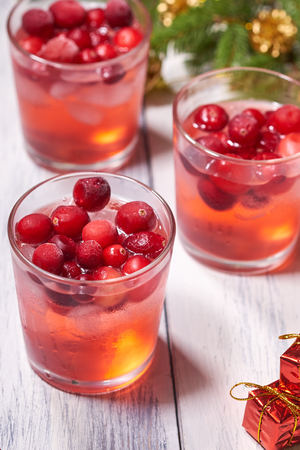 Glasses with cranberry juice on white wooden background with pine branch in the backgroundの写真素材