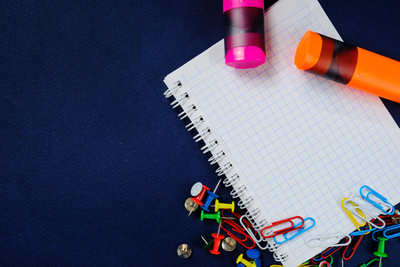school notebook on a blue background, spiral notepad on a   dack blue background with selected areaand colorful clips and markers  . Close upの写真素材
