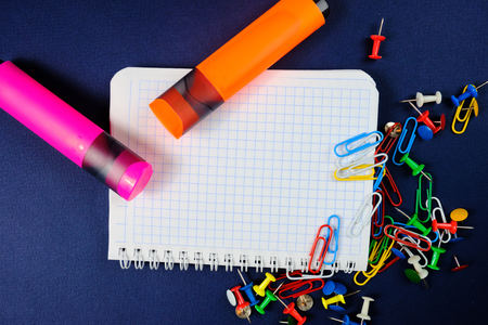 school notebook on a blue background, spiral notepad on a   dack blue background with selected areaand colorful clips and markers  . Close upの写真素材