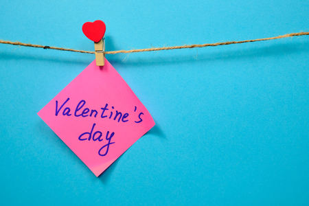 Pink  paper for notes  on the clothespin with hearts  on a blue background. Close upの写真素材