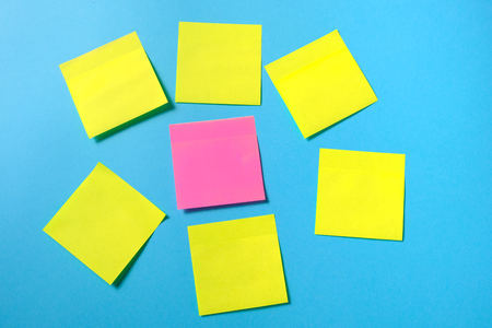 Mock-up many colored empty office stickers on a blue background and one separately. Close upの写真素材
