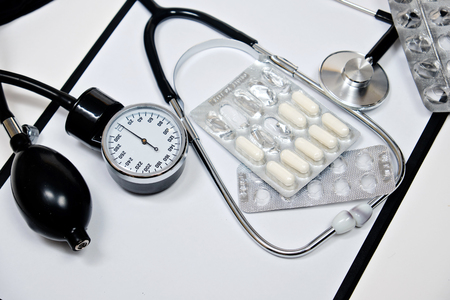 phonendoscope and tonometer  with a folder with white sheets of paper and pills  on a white background. Close upの写真素材