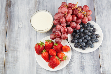 Strawberry, blueberry with yogurt and grapes on wooden backgroundの写真素材