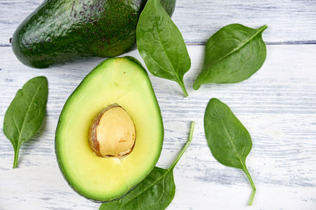 Slices of avocado on white background. Whole and half with leaves.の写真素材