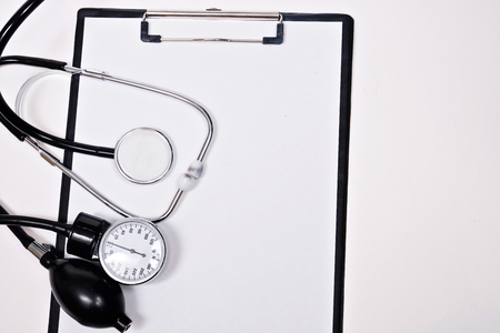 phonendoscope and tonometer with a folder with white sheets of paper  on a white backgroun. Close upの写真素材