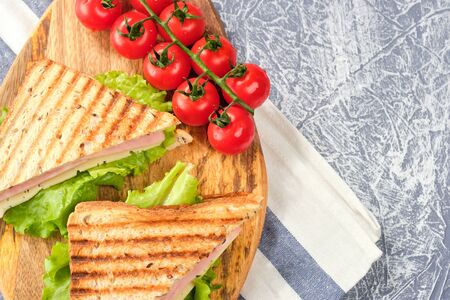 Half of a sandwich in the form of a triangle on a wooden board. The sandwich is decorated with a...