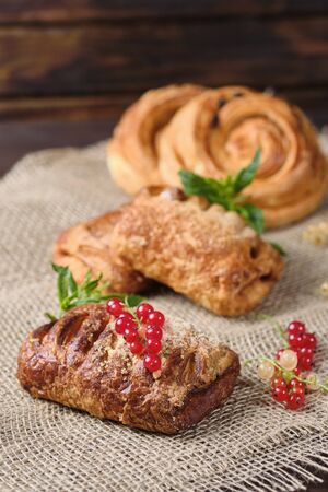 puffs with berry filling with sprigs of fresh red and white currants on burlap and dark wooden background. Close-up. Selective focusの写真素材