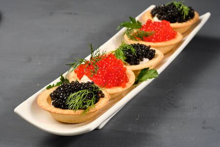 tartlets with red and black caviar on a white plate with lemon on a gray background. Close-upの写真素材