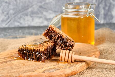 honeycomb with honey on a wooden Board, with a spoon of honeyの写真素材