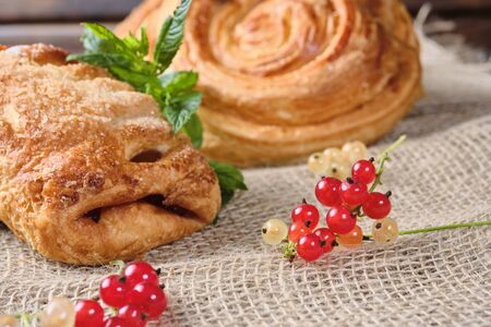 puffs with berry filling with sprigs of fresh red and white currants on burlap and dark wooden background. Close-up. Selective focusの写真素材