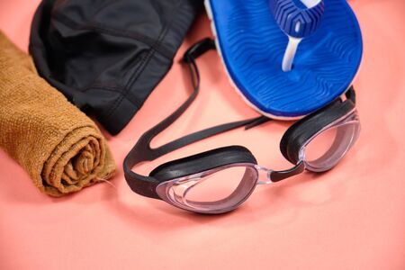 Accessories for swimming in the pool, glasses, cap, slates on a pink backgroundの写真素材