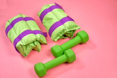 Fitness equipment, green dumbbells and weights on a pink background,の写真素材