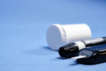 The glucometer with the test strip on a blue background.
