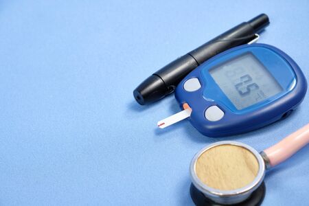The glucometer with the test strip on a blue background.の写真素材