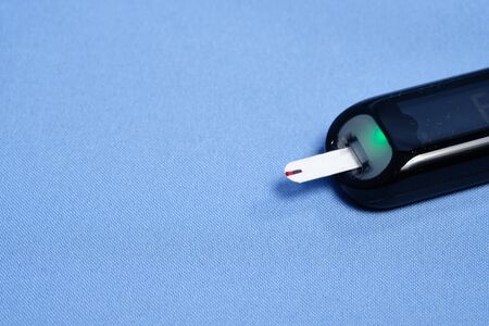 The glucometer with the test strip on a blue background.の写真素材