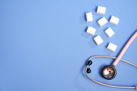 Pink stethoscope, sugar cubes on a blue background, diabetes.の写真素材