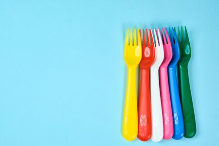Multicolored plastic dishes on a blue background. The concept of environmental pollution by plastic, ecology. place for text,の写真素材