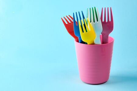 Multicolored plastic dishes on a blue background. The concept of environmental pollution by plastic, ecology. place for text,の写真素材