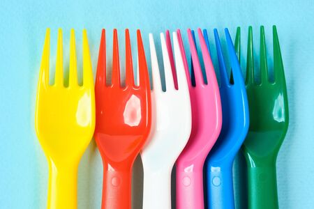 Multicolored plastic dishes on a blue background. The concept of environmental pollution by plastic, ecology. place for text,の写真素材