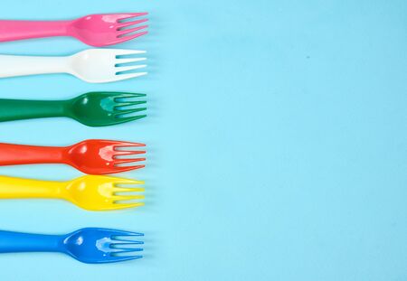 Multicolored plastic dishes on a blue background. The concept of environmental pollution by plastic, ecology. place for text,の写真素材