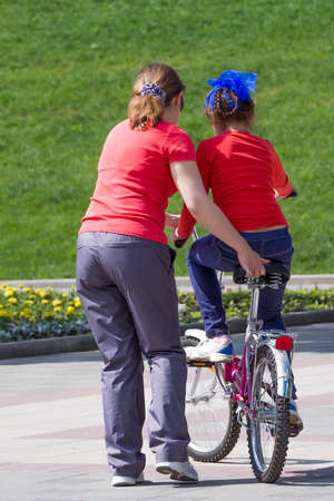 Mother teaches the daughter to ride a two-wheeled bicycleの写真素材