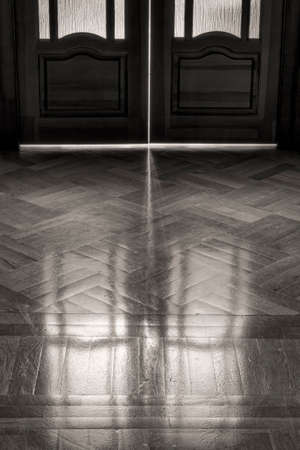 The door of childhood memories  Reflection on the parquet floor closed door in retro style  The concept of elapsed time, background  black and white の写真素材