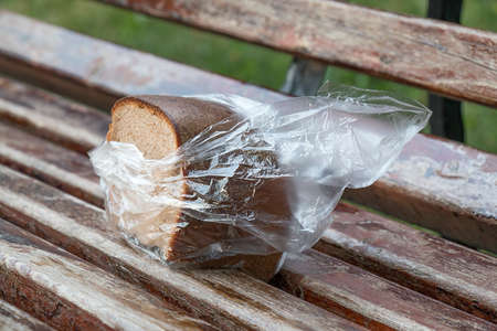 The forgotten bread on a bench in a transparent plastic bagの写真素材