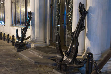 Two ship anchors before an entrance to the building at nightの写真素材