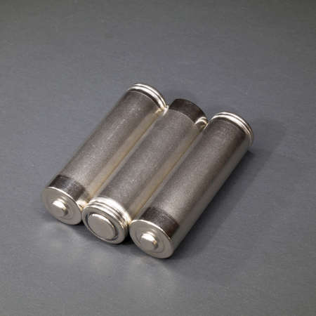 Three AA size metal batteries on a dark background