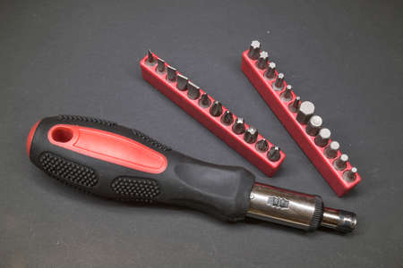 Screwdriver with interchangeable bits on a dark background