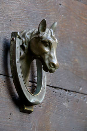 Old wooden door with door knocker in form of the horse head and horseshoeの写真素材