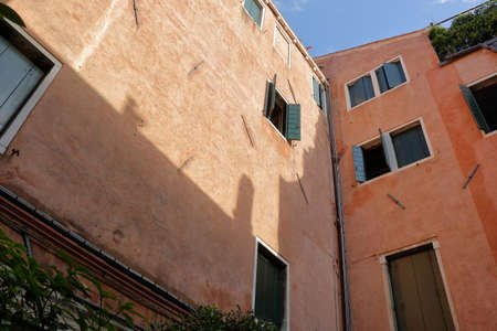 Old orange wall with green shutters on windows in Venice, Italyのeditorial素材