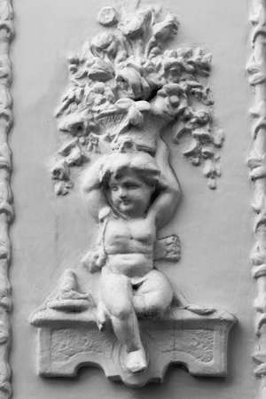 Old stucco molding in the form of a child with basket of flowersの写真素材