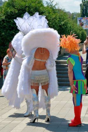 Kislovodsk, Russia - July 18, 2015: The clown in the red wig looks on the back of a woman dressed in...