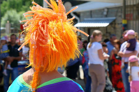 The clown with red wig looks at the crowd of peopleの写真素材