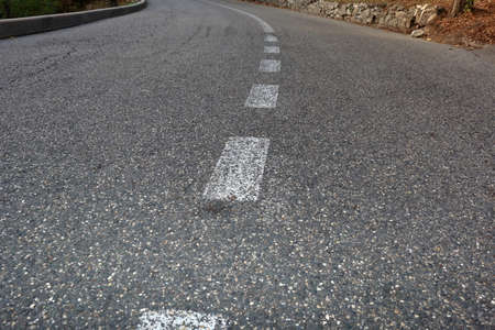 Paved road with dividing line in evening. Focus on foreground