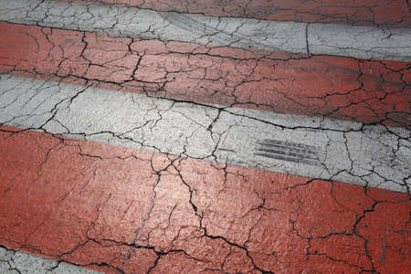 Old red and white road marking on an asphalt road with cracks and track of tires. Abstract...