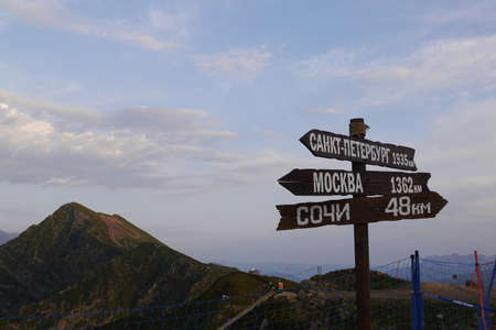 Signs with directions on the background of Caucasus Mountains. Sunset in the ski resort of Rosa Khutor. Sochi, Krasnaya Polyana, Russiaの写真素材