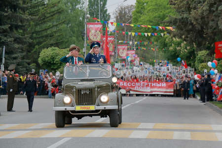 Pyatigorsk, Russia - May 9, 2017: Old UAZ car with veterans is ahead the column Immortal Regiment. Participants column Immortal Regiment bear posters with the image of his relatives died in the battleのeditorial素材