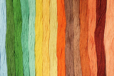 Multicolored cotton threads for embroidery are arranged in a row. Background