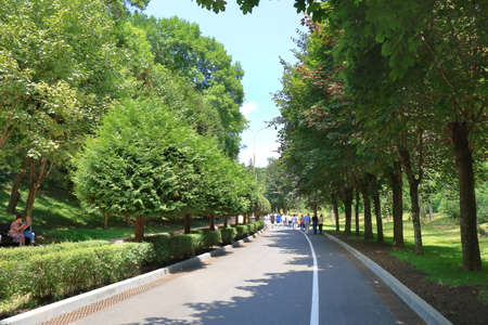 Kislovodsk, Stavropolsky Region, Russia - July 16, 2017: A group of tourists walking along an asphalt road through a forest in a public park in Kislovodskのeditorial素材