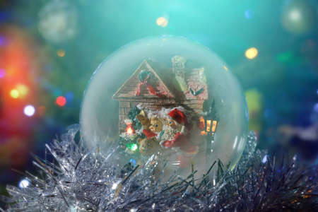 Santa Claus with a child next to the house and a street lamp. Musical snow globe with illumination close-up. Long exposure time. Soft focus and glowの写真素材