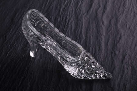 Crystal glass Cinderella shoes on a dark stone background. Glass fashion accessory.の写真素材