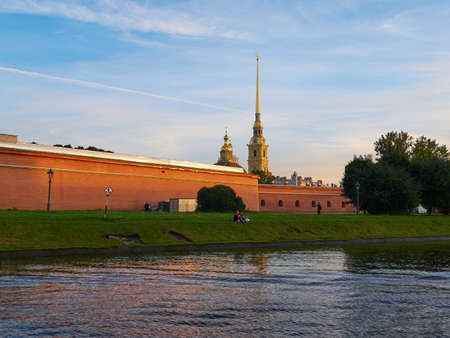 Saint Petersburg, Russia - August 8, 2017: View of the Peter and Paul Fortress at sunset from the boat in Kronverkskiy channel. Tourists are resting on a riverbankのeditorial素材
