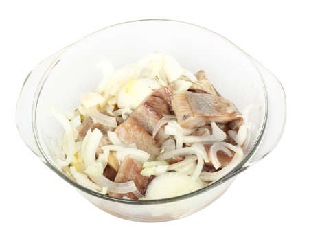 Sliced salted herring with fresh onion in a glass bowl isolated on a white backgroundの写真素材