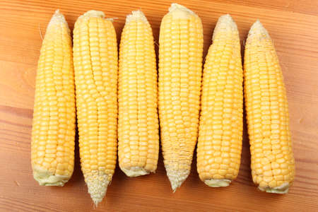Ripe corn heads in a row on a wooden table